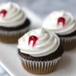chocolate cupcakes with white frosting and red vampire bite gel on marble tray