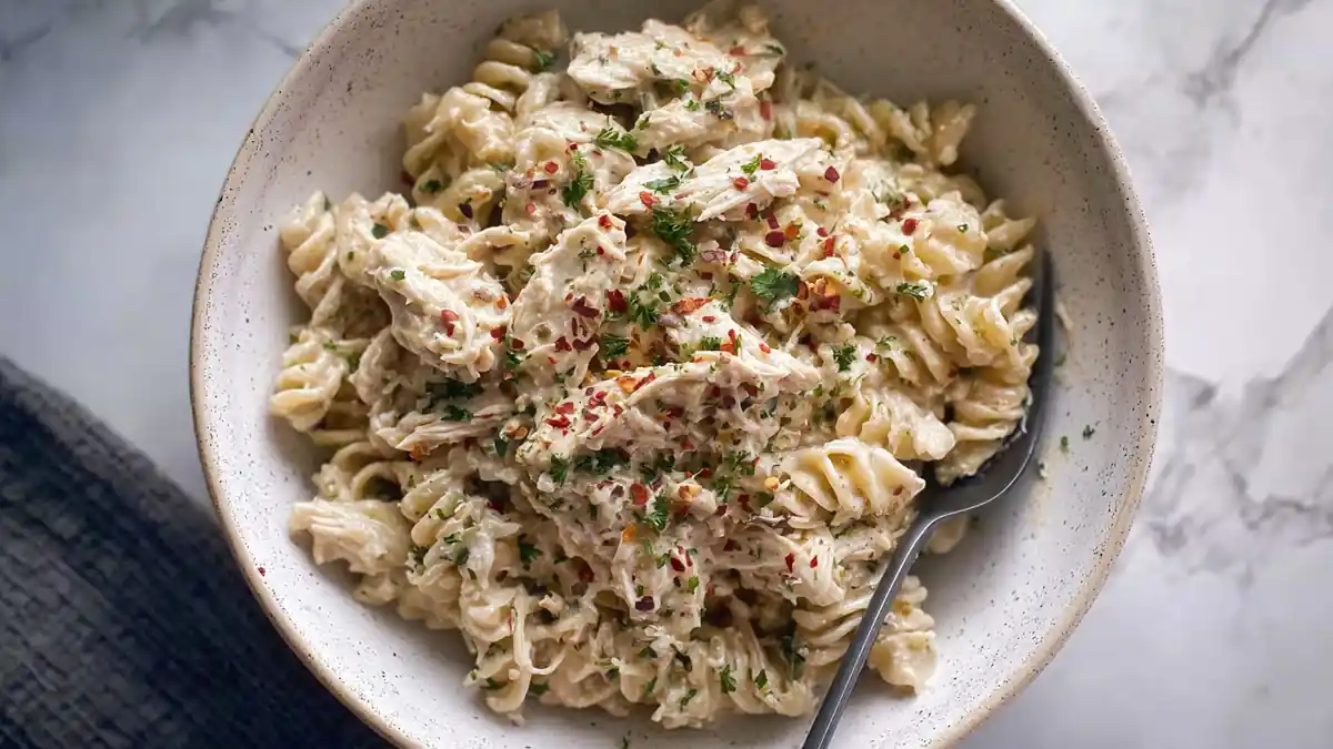 creamy garlic rotini pasta with shredded chicken and red pepper flakes