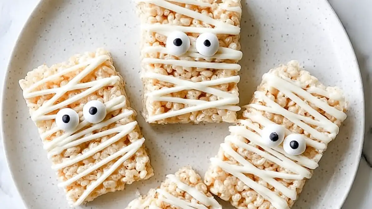 halloween rice krispies treats decorated like mummies with candy eyes and white chocolate drizzle