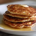 stack of golden buttermilk pancakes topped with syrup and butter