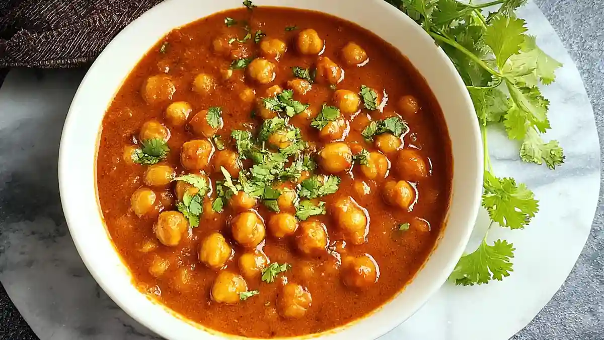 bowl of chickpea curry garnished with fresh cilantro on a marble plate