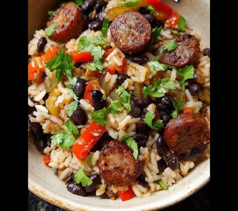 A flavorful plate of black beans and rice with sausage, garnished for a hearty meal.