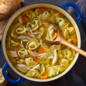 Bowl of easy chicken tortellini soup with fresh herbs and vegetables.